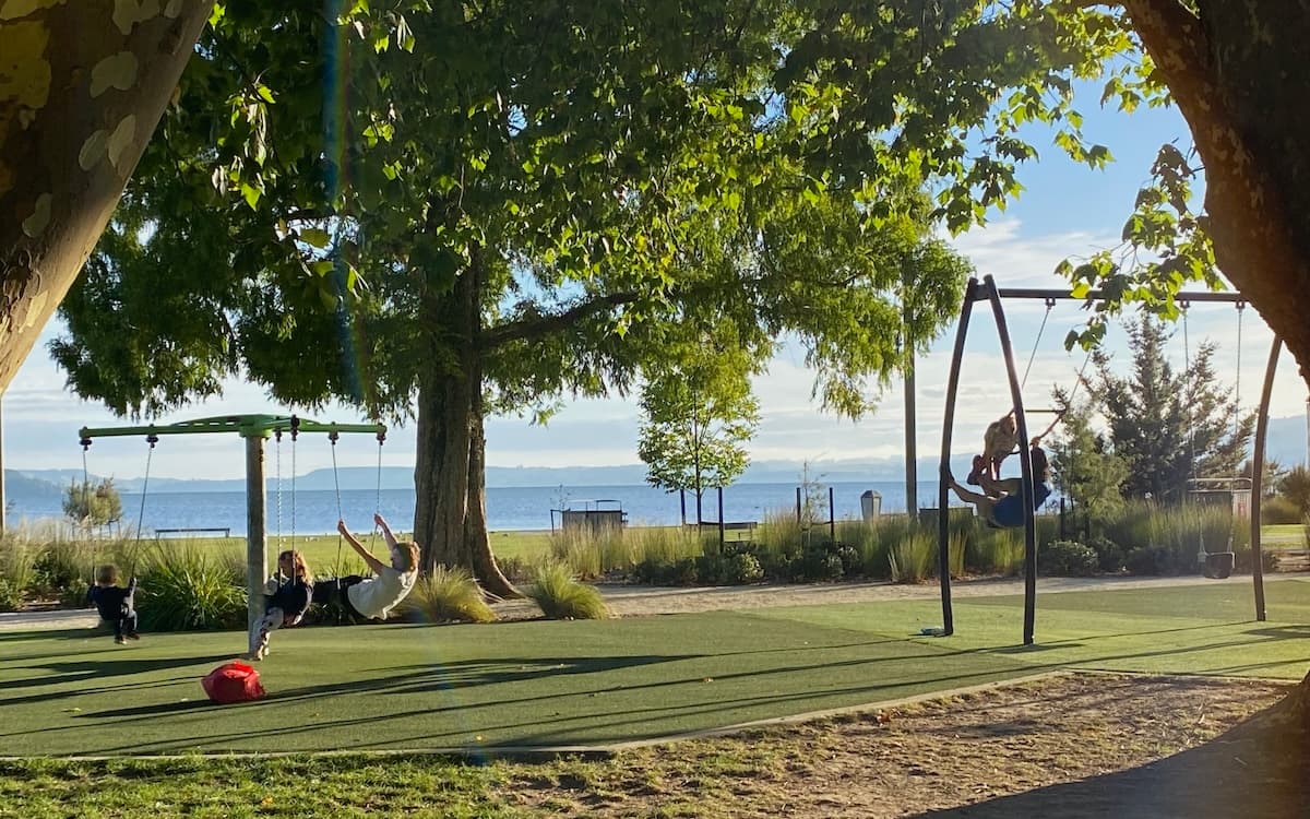 Families on swings at Rotorua lakeside playground.
